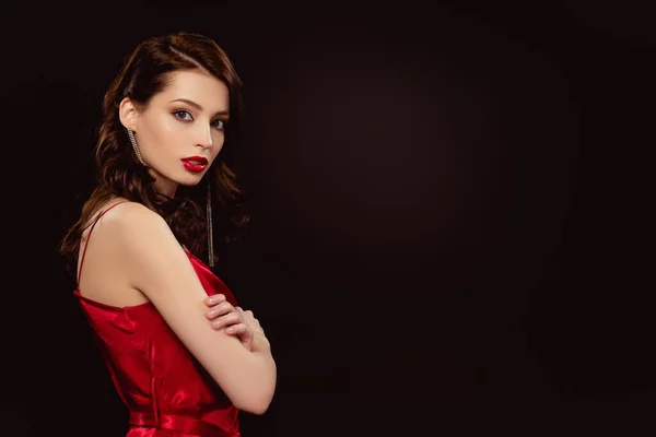 Side view of elegant girl with crosses arms looking at camera isolated on black — Stock Photo