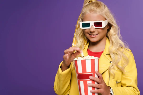 Enfant souriant avec des lunettes 3D tenant seau avec pop-corn sur fond violet — Photo de stock