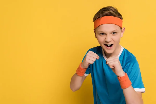 Aggressive kid showing fists and screaming on yellow background — Stock Photo