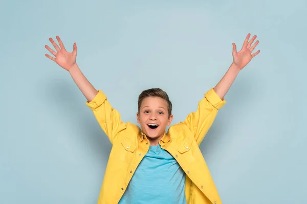 Glückliches Kind mit ausgestreckten Händen, das in die Kamera auf blauem Hintergrund blickt — Stockfoto