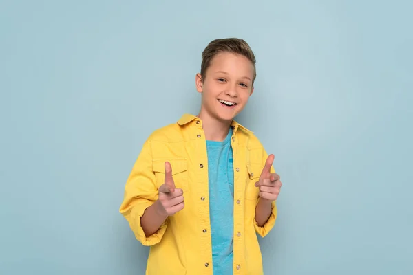 Smiling and cute kid pointing with fingers on blue background — Stock Photo