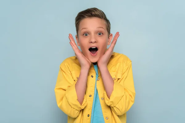 Shocked and cute kid looking at camera on blue background — Stock Photo