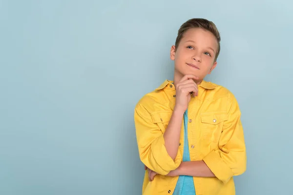 Thoughtful kid looking up on blue background with copy space — Stock Photo