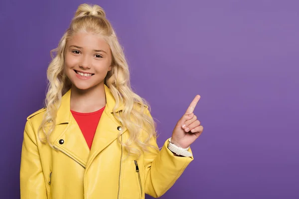 Smiling and cute kid pointing with finger on purple background — Stock Photo