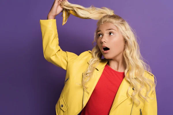 Chocado e bonito garoto tocando cabelo no fundo roxo — Fotografia de Stock