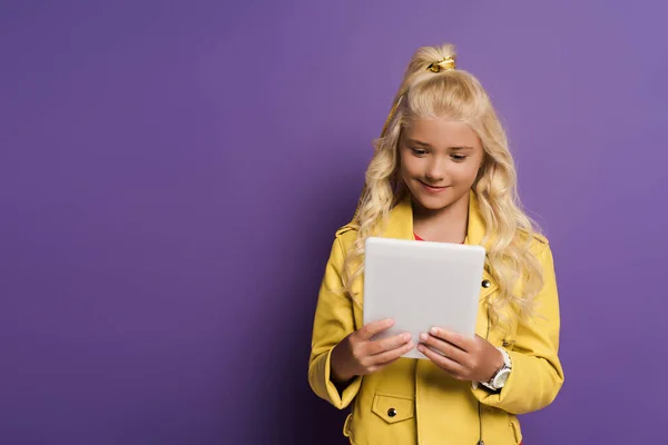 Smiling kid using digital tablet on purple background with copy space — Stock Photo