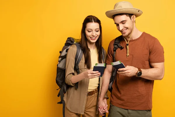 Pareja de viajeros felices con mochilas con pasaportes y billetes en amarillo - foto de stock