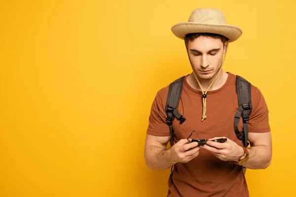 Viajero guapo mirando brújula en amarillo - foto de stock