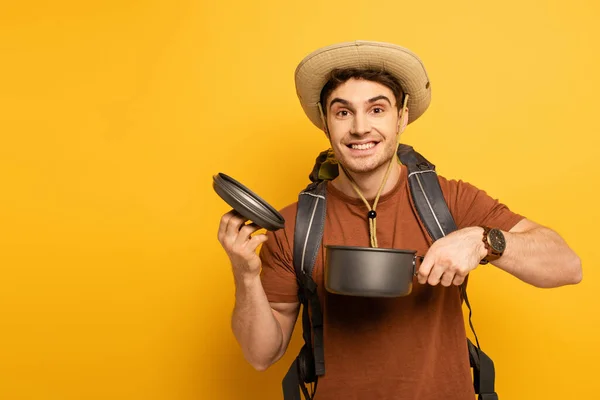 Handsome smiling traveler holding pot on yellow — Stock Photo
