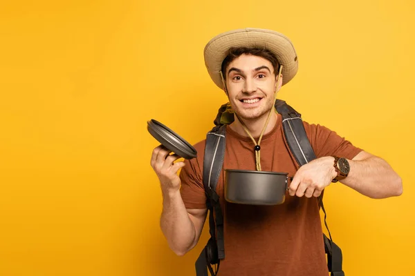 Beau voyageur souriant tenant pot sur jaune — Photo de stock