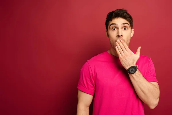 Portrait of shocked man in pink t-shirt on red — Stock Photo