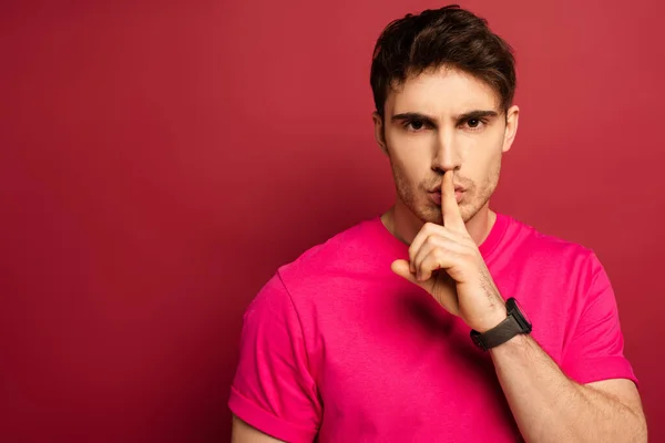 Retrato de homem em camiseta rosa mostrando símbolo de silêncio no vermelho — Fotografia de Stock