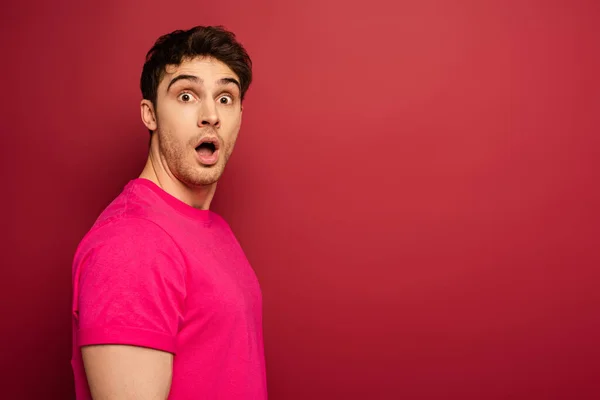 Portrait of shocked man in pink t-shirt on red — Stock Photo