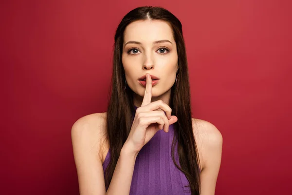 Portrait of beautiful woman showing silence symbol on red — Stock Photo