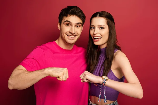 Красива позитивна молода пара дає кулакові удари на червоному — стокове фото