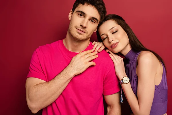 Schönes junges Paar, das sich mit geschlossenen Augen auf Rot umarmt — Stockfoto