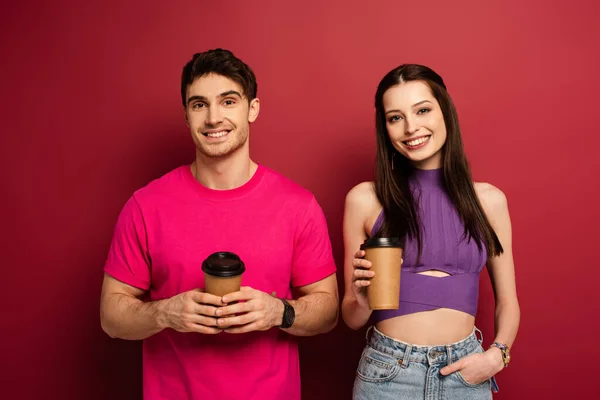 Beautiful happy couple holding coffee to go on red — Stock Photo