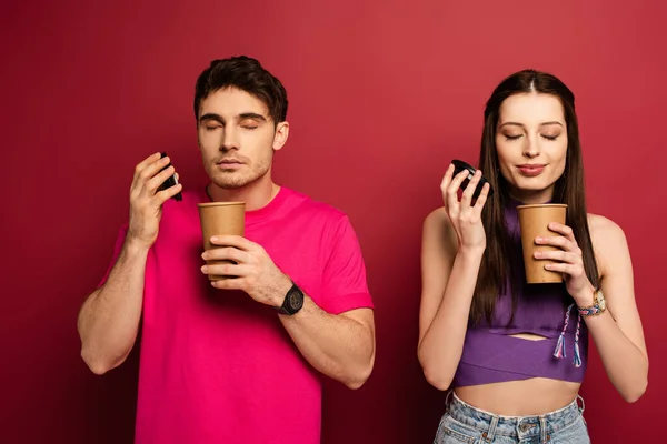 Beautiful couple smelling coffee to go on red — Stock Photo