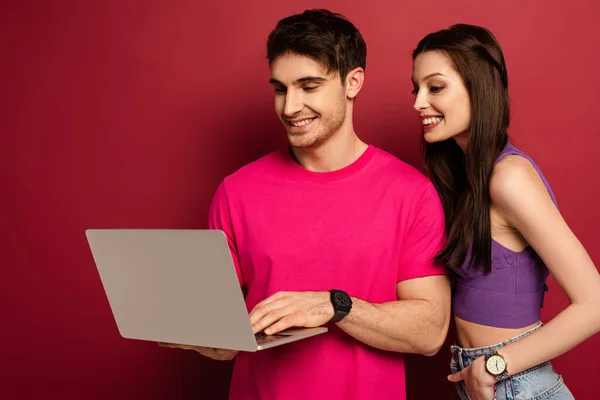 Beautiful happy couple using laptop together on red — Stock Photo