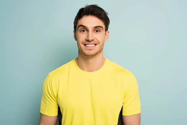 Fröhlicher Sportler in gelbem T-Shirt auf blauem Grund — Stockfoto