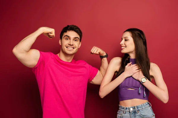 Сильный мускулистый мужчина с веселой девушкой на красном — стоковое фото