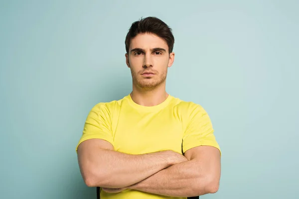 Serious muscular sportsman with crossed arms on blue — Stock Photo