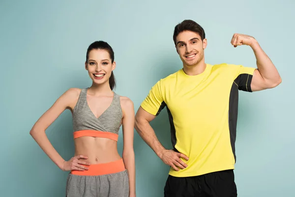 Счастливая атлетическая пара, стоящая в спортивной одежде на голубом — стоковое фото