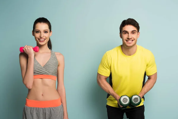 Entrenamiento de pareja atlética feliz con pesas en azul - foto de stock