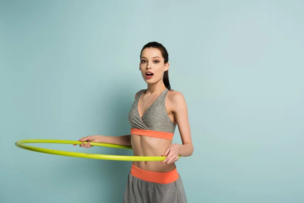 Smiling sportswoman training with hula hoop on blue — Stock Photo