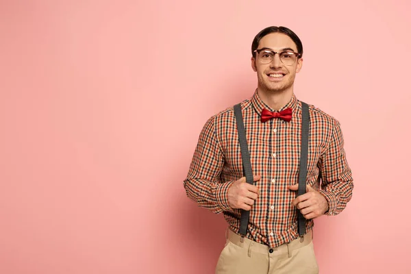 Nerd masculino sonriente en anteojos y tirantes en rosa - foto de stock