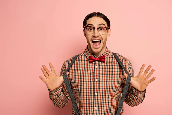 Возбужденный мужчина ботан в очках и подтяжках на розовом — стоковое фото