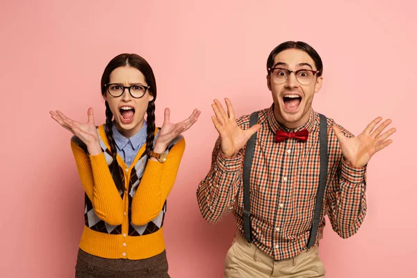 Par de nerds sorprendidos en anteojos gritando en rosa - foto de stock