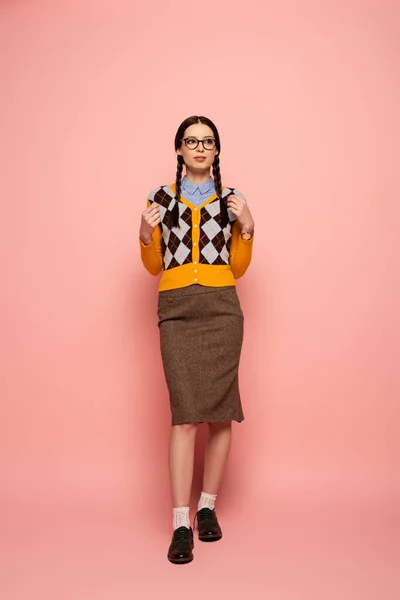Pensativo nerd femenino en gafas de pie en rosa - foto de stock