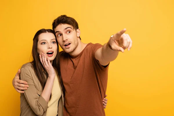Couple of excited travelers pointing isolated on yellow — Stock Photo