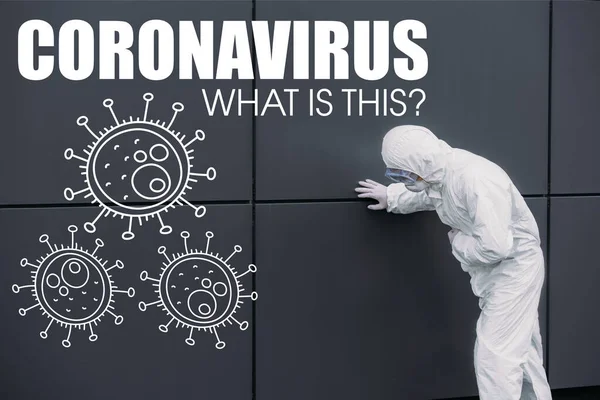 Asian epidemiologist in hazmat suit leaning on wall while suffering from symptomatic abdominal pain, coronavirus illustration — Stock Photo