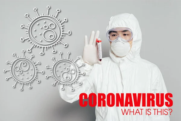 Asiatischer Epidemiologe in Schutzanzug und Atemmaske zeigt Reagenzglas mit Blutprobe auf grauem Hintergrund, Coronavirus-Illustration — Stockfoto