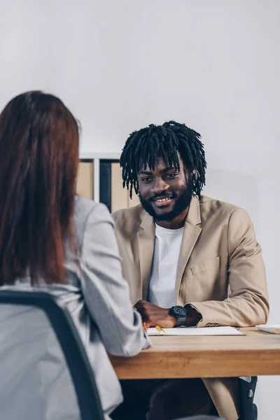 Enfoque selectivo del reclutador afroamericano que realiza una entrevista de trabajo con un empleado en la oficina - foto de stock
