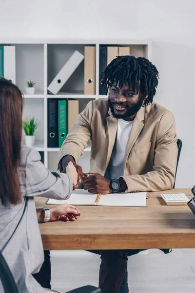 Vue recadrée d'un recruteur afro-américain serrant la main d'un employé lors d'un entretien d'embauche au bureau — Photo de stock