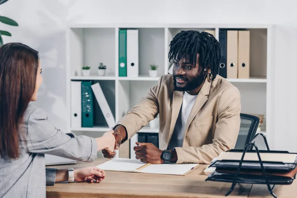Reclutador afroamericano estrechando la mano con empleado en entrevista de trabajo en la oficina - foto de stock