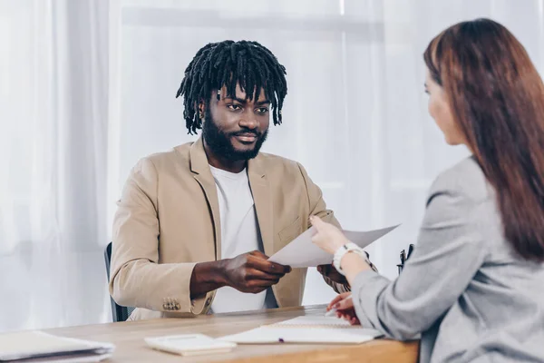 Enfoque selectivo de empleado afroamericano dando papeles al reclutador en entrevista de trabajo en la oficina - foto de stock