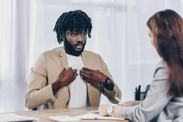 Foco seletivo do funcionário afro-americano apontando a si mesmo e olhando para o recrutador na entrevista de emprego no escritório — Fotografia de Stock