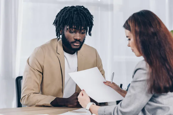 Selektiver Fokus des Recruiters beim Blick auf Papier in der Nähe besorgter afrikanisch-amerikanischer Mitarbeiter beim Vorstellungsgespräch im Büro — Stockfoto