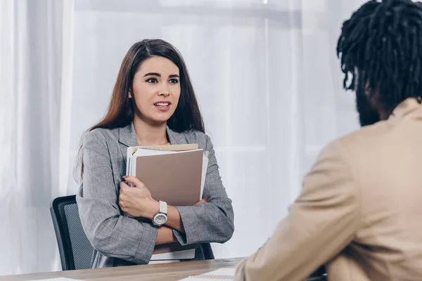 Selective focus of worried employee with documents and african american recruiter looking at each other at job interview in office — Stock Photo