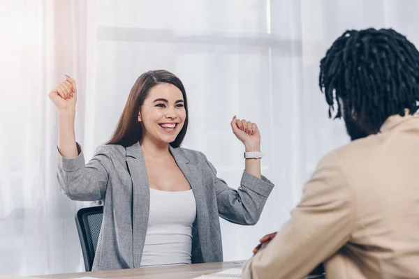 Selective focus of happy and excited employee with african american recruiter at job interview in office — Stock Photo