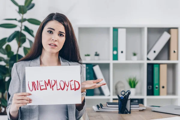 Dipendente preoccupato mostrando cartello con scritte disoccupate in ufficio — Foto stock