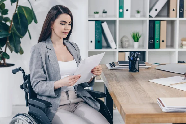 Disabled recruiter on wheelchair looking at paper at table in office — Stock Photo