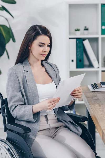 Disabled recruiter on wheelchair looking at paper in office — Stock Photo