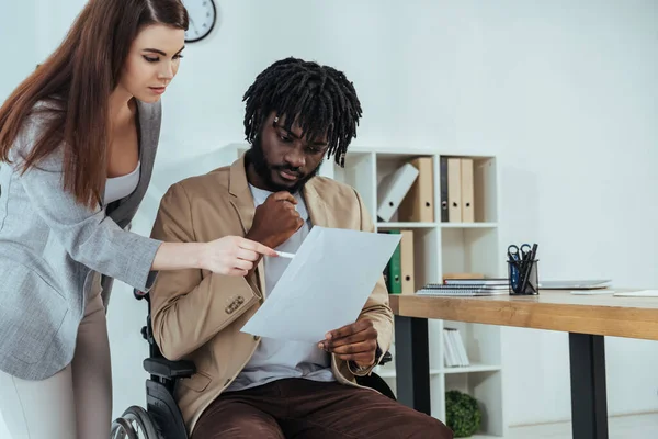 Employee pointing at papers in african american male hands in office — Stock Photo