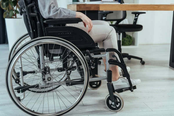 Partial view of disabled employee in wheelchair at table in office — Stock Photo