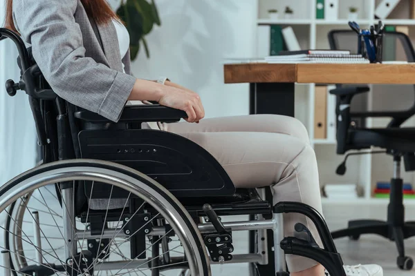 Vista cortada do trabalhador deficiente em cadeira de rodas à mesa no escritório — Fotografia de Stock